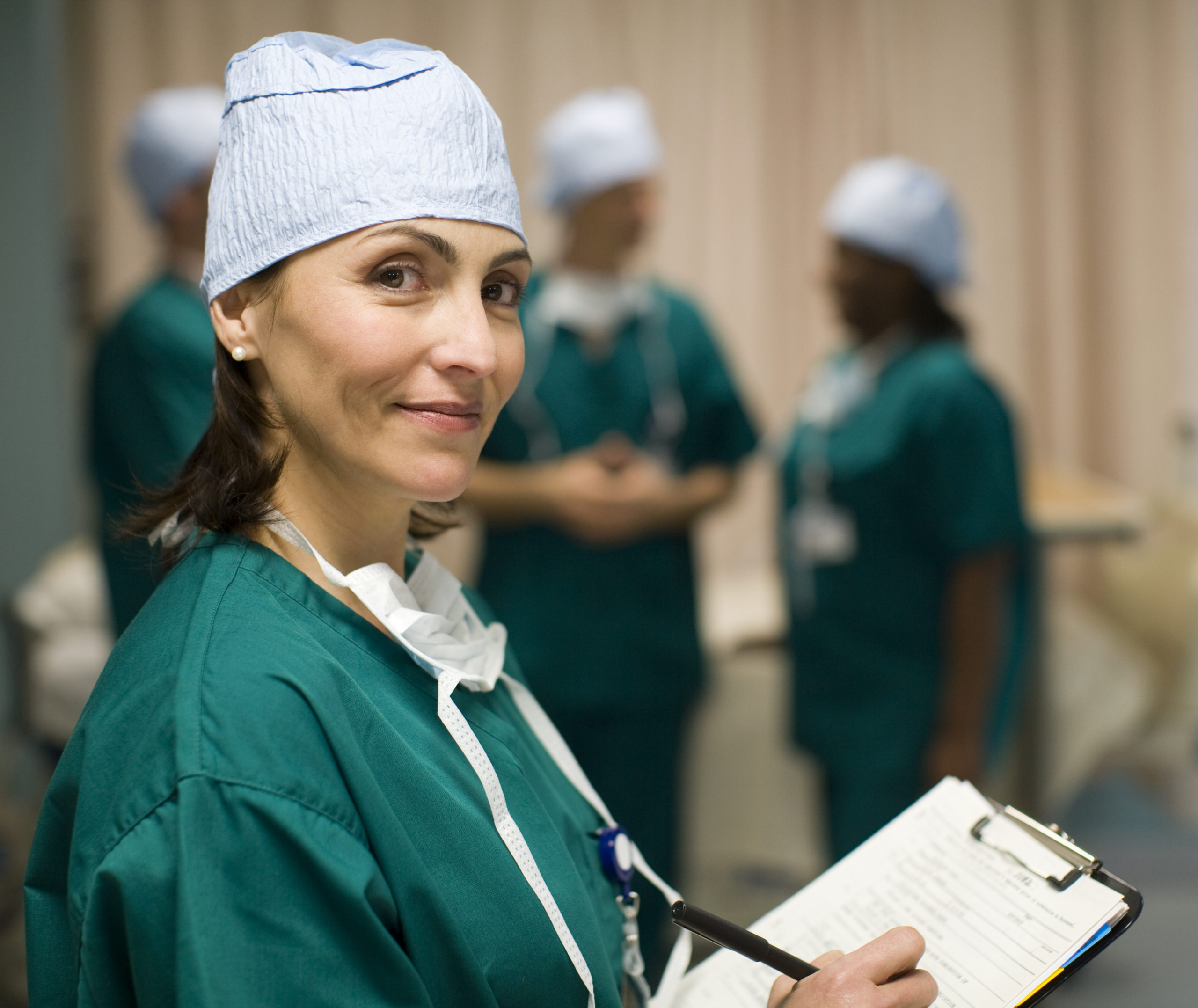 female surgeon smiling confidently as she checks a patient chart, her operating room is optimized